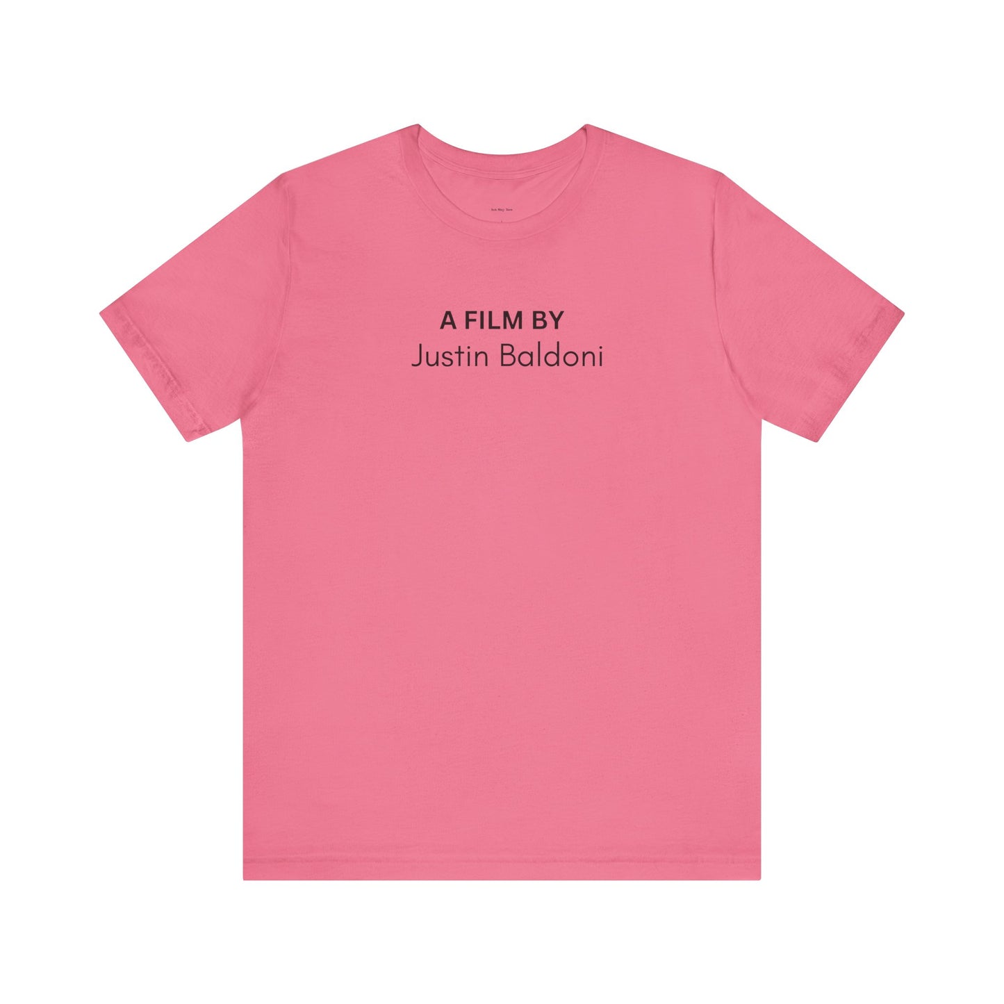 Pink t-shirt with black text 'A Film By Justin Baldoni'
